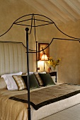 A canopy bed frame made of curved metal in a country style bedroom