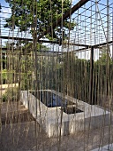 Art installation around a stone trough with water under a pergola