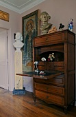 Antique secretary with a writing desk and busts in front of a pink wall