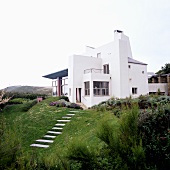 A newly built, white cubic house with a garden on the English coast