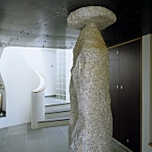 Skulptur aus Granit im Vorraum vor geschwungenem Treppenaufgang