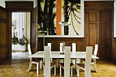 Holzvertäfeltes Esszimmer einer Villa mit weisser Esstischgarnitur im Designerstil