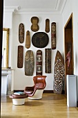 Wohnraumecke eines Altbaus - Ledersessel mit Fussschemel vor afrikanischer Kunstsammlung an der Wand