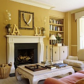 A living room with yellow walls and a coffee table in front of a fireplace and a built-in shelf