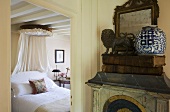 A view from a hallway into a country-style bedroom with a white double bed with a canopy