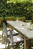 Grey plastic chairs with cushions set around a simple wooden table on a terrace