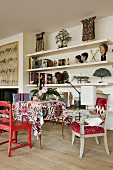 Wohnraum mit farbigen Stühlen und Tisch mit buntem Tischtuch vor weisser Regalwand