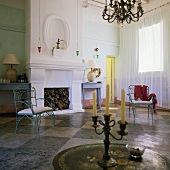 A fireplace room with a black and white tiled floor in a Mediterranean villa - a blue metal chair and an antique candle stick on a table