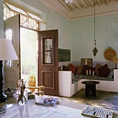 Wohnraum im Mediterraner Haus mit gemauerter Polstersitzecke und offener Haustür mit Gartenblick