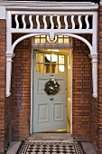 A house in London - front entrance with a brick facade and a Christmas wreath on the white front door