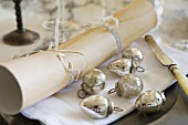 A place setting with silver Christmas baubles and plate decoration