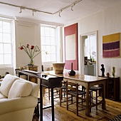 An antique occasional table between a living area and a dining area with a rustic table