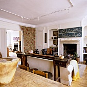 An antique occasional table in front of a sofa in a fireplace room with a view through open double doors