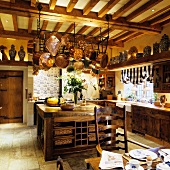 Copper pans hanging above an old kitchen counter in the kitchen of an English country house with a wood beam ceiling
