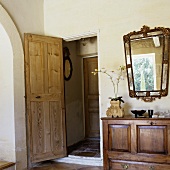 A living room with an open door and an antique sideboard with a mirror