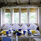 Breakfast in a rustic country house kitchen with white cushions on a comfortable bench