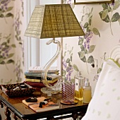 A bedside lamp with a curved acrylic base and a checked lampshade on a bedside table