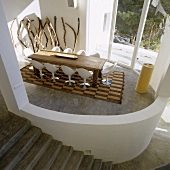 Blick in ovalen offenen Wohnraum mit rustikalem Tisch und Designer Stühlen
