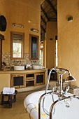 A washstand with mirrors against a yellow wall in the bathroom of a South African house