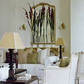 A white sofa and vases of flowers in front of a mirror and a Rococo-style wall table