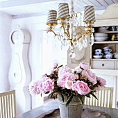 A dining table with a bunch of peonies in a 19th century German thatched-roof house decorated in a Scandinavian style