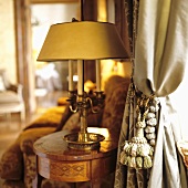 An antique table lamp on a Baroque table and a curtain with a cord tie