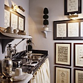 A tea kitchen in a corner of a room and a collection of pictures on a pastel-coloured wall