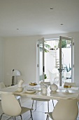 Breakfast in a white dining room with a view through an open terrace door