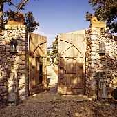 A natural stone wall with a rustic wooden door in Mediterranean surroundings