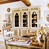 A desk in front of a decorative, Spanish-style crockery cabinet
