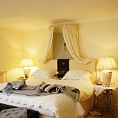 Warm lamplight in a yellow-painted bedroom with a canopy above the bed