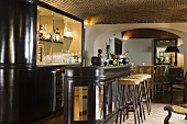 A bar lounge with a brick ceiling - a black bar with bar stools