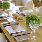 Oriental place settings at a wooden table with wine glasses and fresh herbs