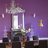 A long table with a chandelier and a mirror hung on a purple wall