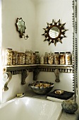 A corner of a bathroom - a carved wooden console and storage jars with a star-shaped mirror