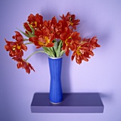 Red tulips in a blue vase on a wall bracket