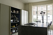 A black kitchen counter and an open kitchen cupboard in front of a window