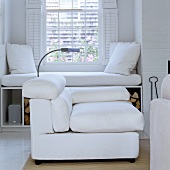 A white upholstered armchair and an upholstered window sill with cushions