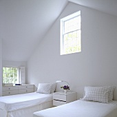A white bedroom - single beds in an attic with a window in the gable wall