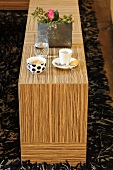 A veneered wooden table set for coffee with a bunch of flowers