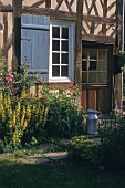 A half-timbered house with a window and blossoming flowers