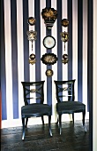 Antike gepolsterte Stühle vor weiss-blau gestreifter Wand