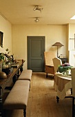 Gepolsterte Bänke und Sessel auf rustikalem Dielenboden mit Blick auf graue Zimmertür