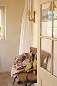 An open glass door - coffee break on an antique wooden bench with cushions and a blanket