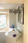 A bathroom in a country house - a curved basin with an antique mirror on a white mosaic-tiled wall