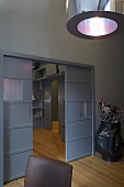 A grey room - a pendent lamp with a metal shade and sliding doors on a continuous parquet floor