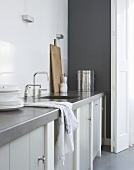A grey kitchen counter with a sink and a cupboard underneath