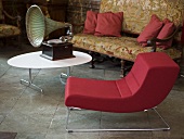 Red upholstered chair with metal frame and gramophone on a white coffee table in front of a sofa