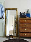 Full length mirror with a good frame next to an antique wooden chest of drawers