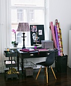 Work area in a mix of styles - black desk with Bauhaus chair in front of a window and bolts of fabric in a container
